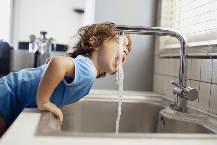 Chłopiec pijący wodę z kranu